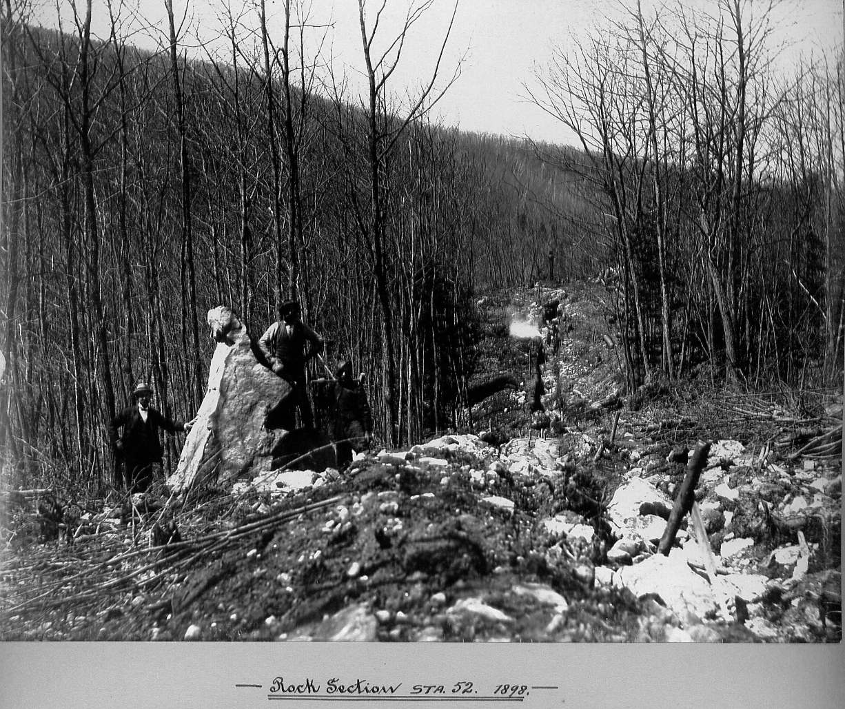 Men standing next to large rock in woods