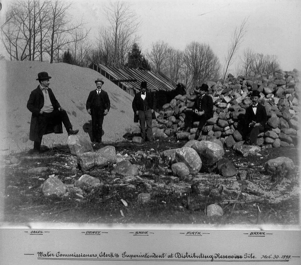 Water Commissioners standing and sitting on large rocks at Sackett Reservoir